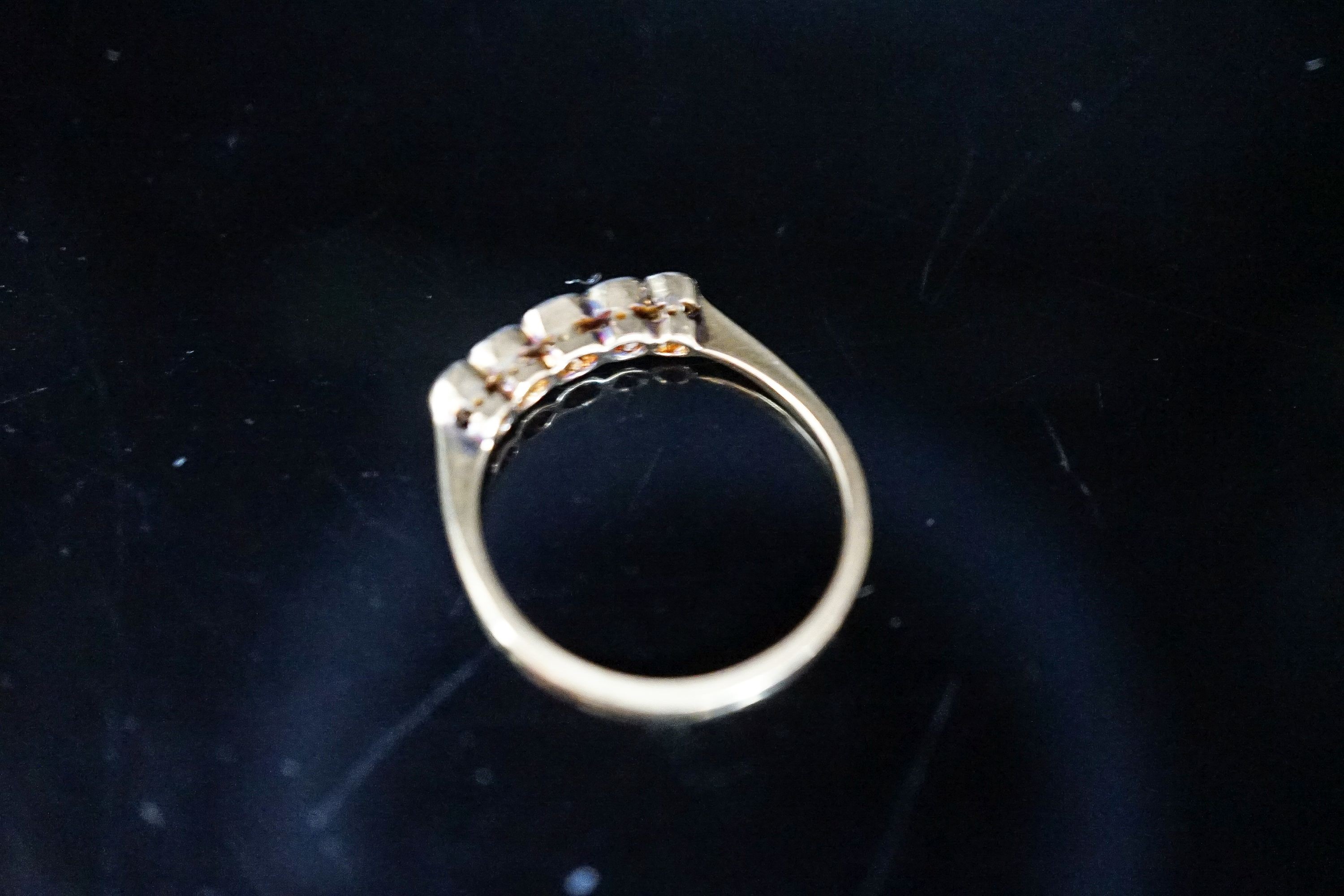 An 18ct, plat and graduated three stone diamond set half hoop ring, size M, gross weight 1.9 grams.